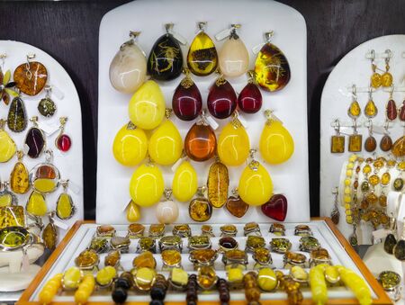 Various natural amber necklaces, earrings and pendants in glass case of jewelry storeの写真素材