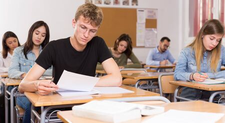 Young boy is writing test and thinking about questions at the desk in the class.の写真素材