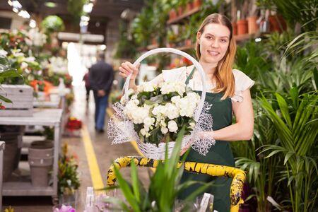 Female florist delivering pots of flowers on a pushcartの写真素材