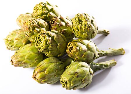Uncooked green artichokes on a white surfaceの写真素材