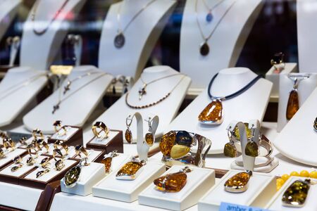 Various examples of jewelry made of amber mounted in precious metals offered for sale on showcase of shopの写真素材