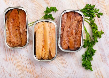 Open can of preserved natural fillet of frigate tuna on wooden table with fresh parsleyの写真素材