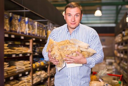 Portrait of ordinary man buying pasta in supermarketの写真素材