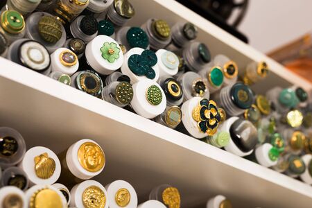 BARCELONA, SPAIN - OCTOBER 18, 2019: Large assortment of colored buttons of various design in tubes on needlework store shelvesのeditorial素材