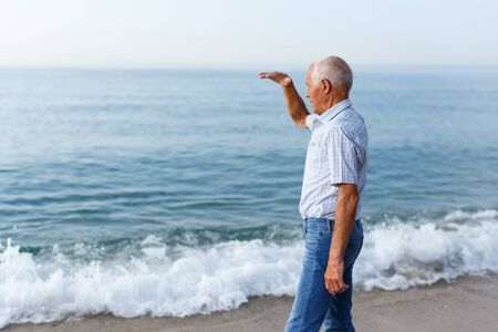 Active elderly man spending time near ocean and looking to something interesting
の写真素材
