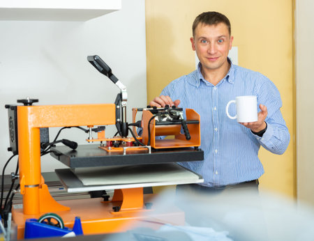 Man uses machine to print on ceramic mug
