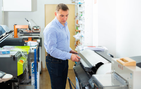 Man uses plotter in small printing shop