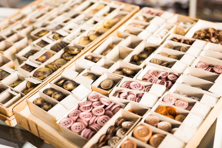 Colored plastic buttons in carton for sale on needlework store showcase