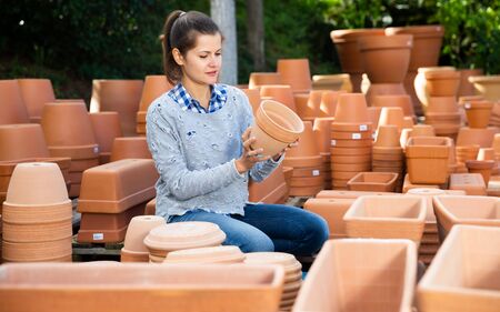 Portrait of female worker of gardening material warehouse checking clay potsの写真素材