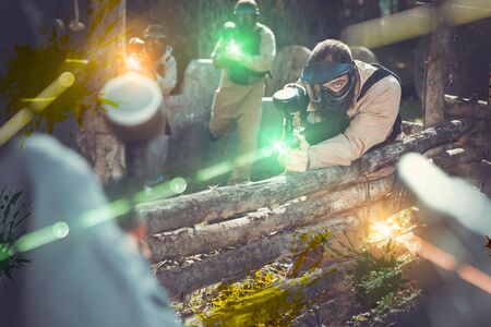Excited male and female paintball players in protective uniform aiming and shooting with gunsの写真素材