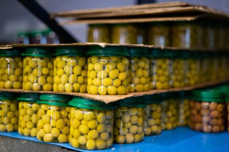 Pickled olives in glass jars at store warehouseの写真素材