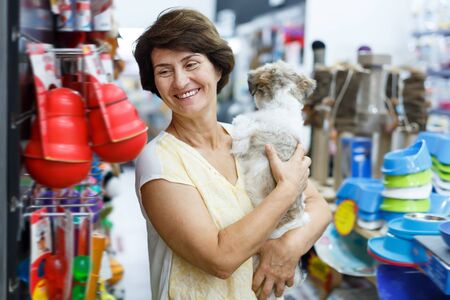 Elderly woman visiting pet shop in search of accessories for her dogの写真素材