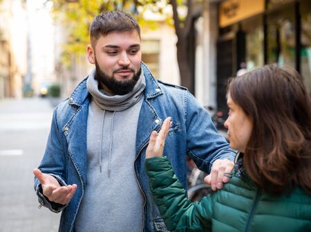 Disgruntled young woman stopping stranger man bothering her on city streetの写真素材
