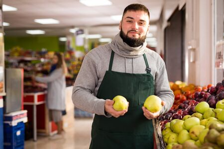 Supermarket employee will lay out ripe apples on the counterの写真素材