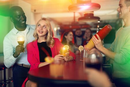 Bartender shaking cocktail for friends, they drinking in nightclubの写真素材