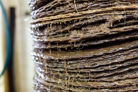 Closeup of stack of fiber mats with grinded olive paste during pressing of olive oil on artisanal...