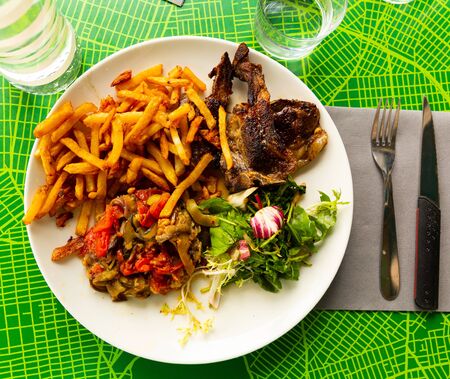 French cuisine. Appetizing grilled mutton ribs with garnish of fresh and marinated vegetablesの写真素材