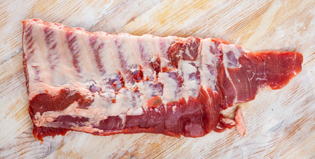 Fresh meaty rack of pork ribs ready for cooking on wooden table