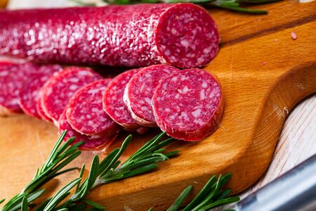 Traditional Spanish jerked sausage of Fuet Nobleza from minced pork seasoned with garlic and pepper with cut slices on wooden surface

の写真素材