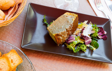 Appetizing leek pie served with greens and sauce