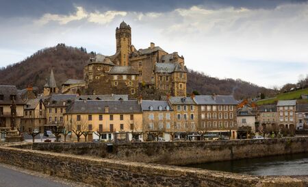 Scenic landscape of French village of Estaing on bank of Lot river with medieval Chateau in cloudy winter dayのeditorial素材