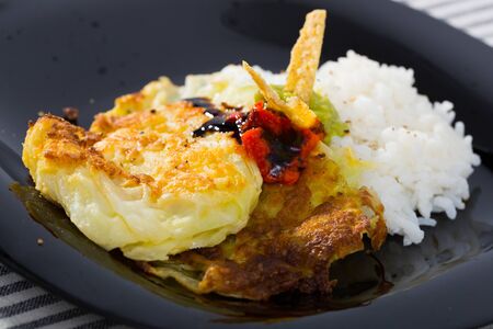 Leaves of cabbage fried in batter served with boiled rice and sauces on black plate

の写真素材
