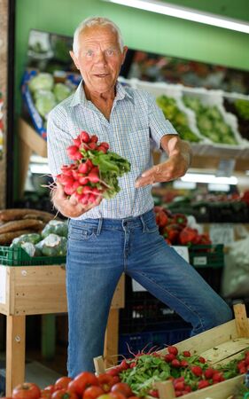 Senior man searching for fresh vegetables while shopping in greengroceryの写真素材