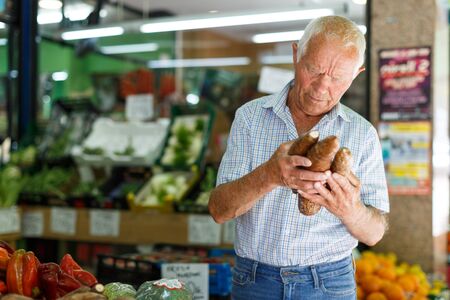 Portrait of older man choosing fresh vegetables in farmer marketの写真素材