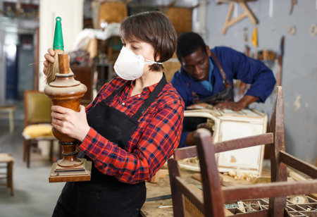 Woman in respiratory mask dusting wooden detail of vintage furnitureの写真素材