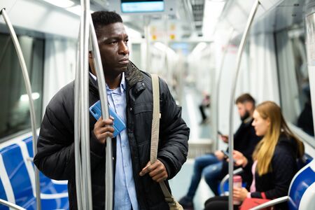 Portrait of thoughtful African American man traveling in modern city subway carの写真素材