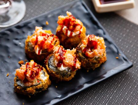 Hot fried futomaki topped with chopped salmon and delicate cream cheese. Traditional Japanese sushiの写真素材