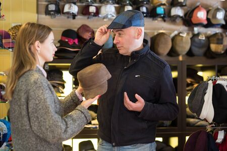 Portrait of stylish couple choosing together new hat for man in shopの写真素材