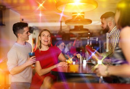 Bartender shaking cocktail for friends, they drinking in nightclubの写真素材