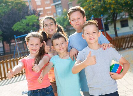 Kids posing at the playground together and thumbs upの写真素材