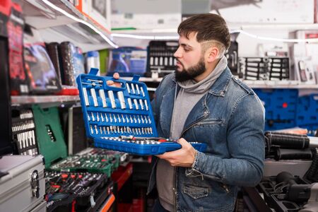 portrait of young male is standing with new ratchet in tools storeの写真素材