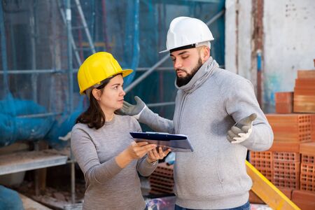 Civil engineers inspecting process of building overhaul, comparing to blueprintsの写真素材