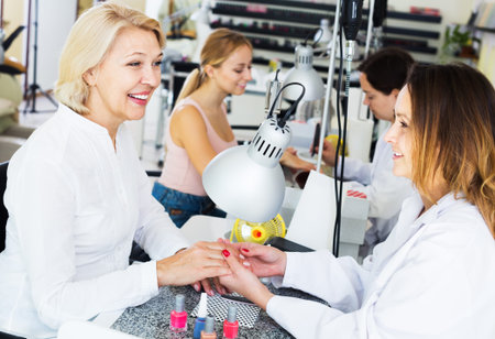 Two women clients having manicure done in nail studioの写真素材