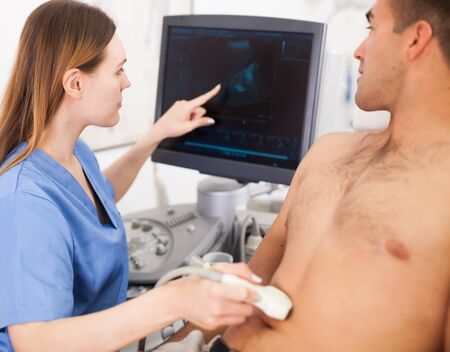 Young woman doctor and patient during the ultrasound examination of abdomen in medical officeの写真素材