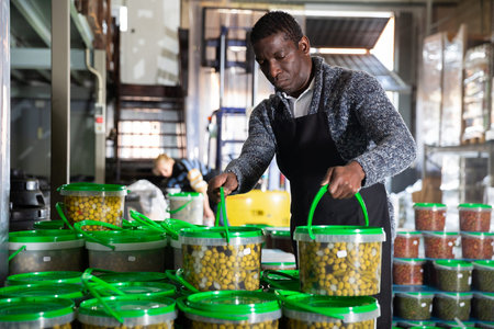 Workman carrying plastic containers with can olives