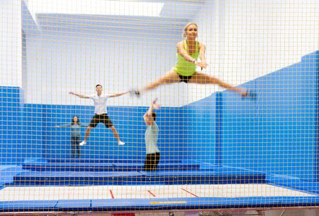 View of yellow safety net in trampoline sports center with blurred young people training on backgroundの写真素材