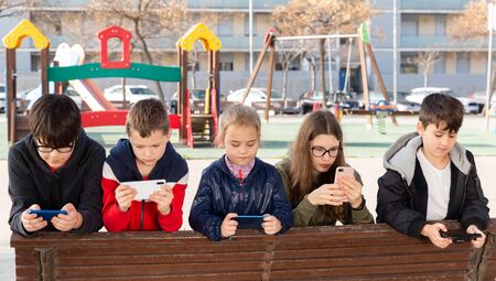 Kids using phones outdoors, concept of children addiction to social networkの写真素材