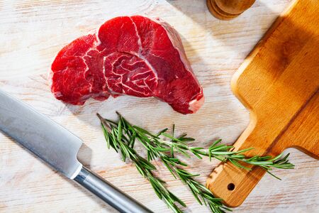 Ingredients for cooking. Fresh raw beef entrecote with rosemary on wooden surfaceの写真素材