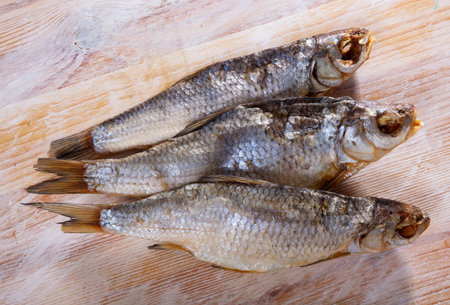 Dried salted caspian roach fish on light wooden background, traditional russian snack