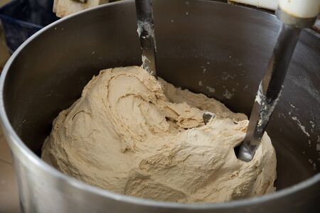 Baker preparing the dough for bread in a dough mixerの写真素材