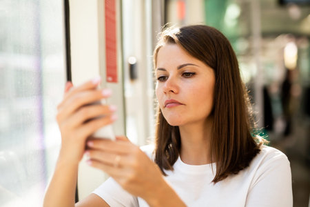 Young woman going to work by bus or trolley and using phone