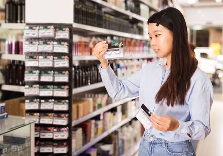 Positive Asian female customer buying false eyelashes in professional cosmetics shopの写真素材