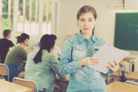 Portrait of girl who is standing satisfied after lecture in the classroom in the school.の写真素材