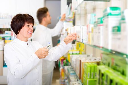 Portrait glad pharmacist and pharmacy technician posing in drugstoreの写真素材
