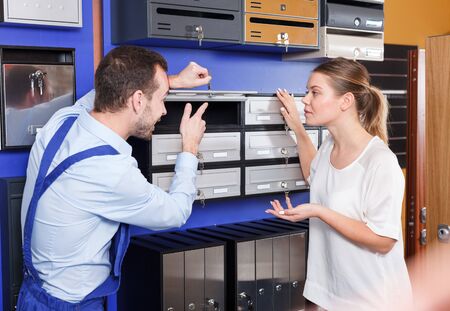 Male worker helping young client woman choosing new mailbox in hardware storeの写真素材