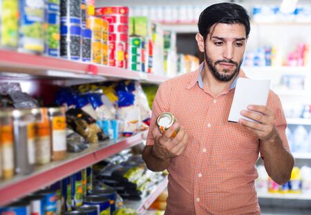 young american   man is choosing Oregano using note list in supermarket.の写真素材